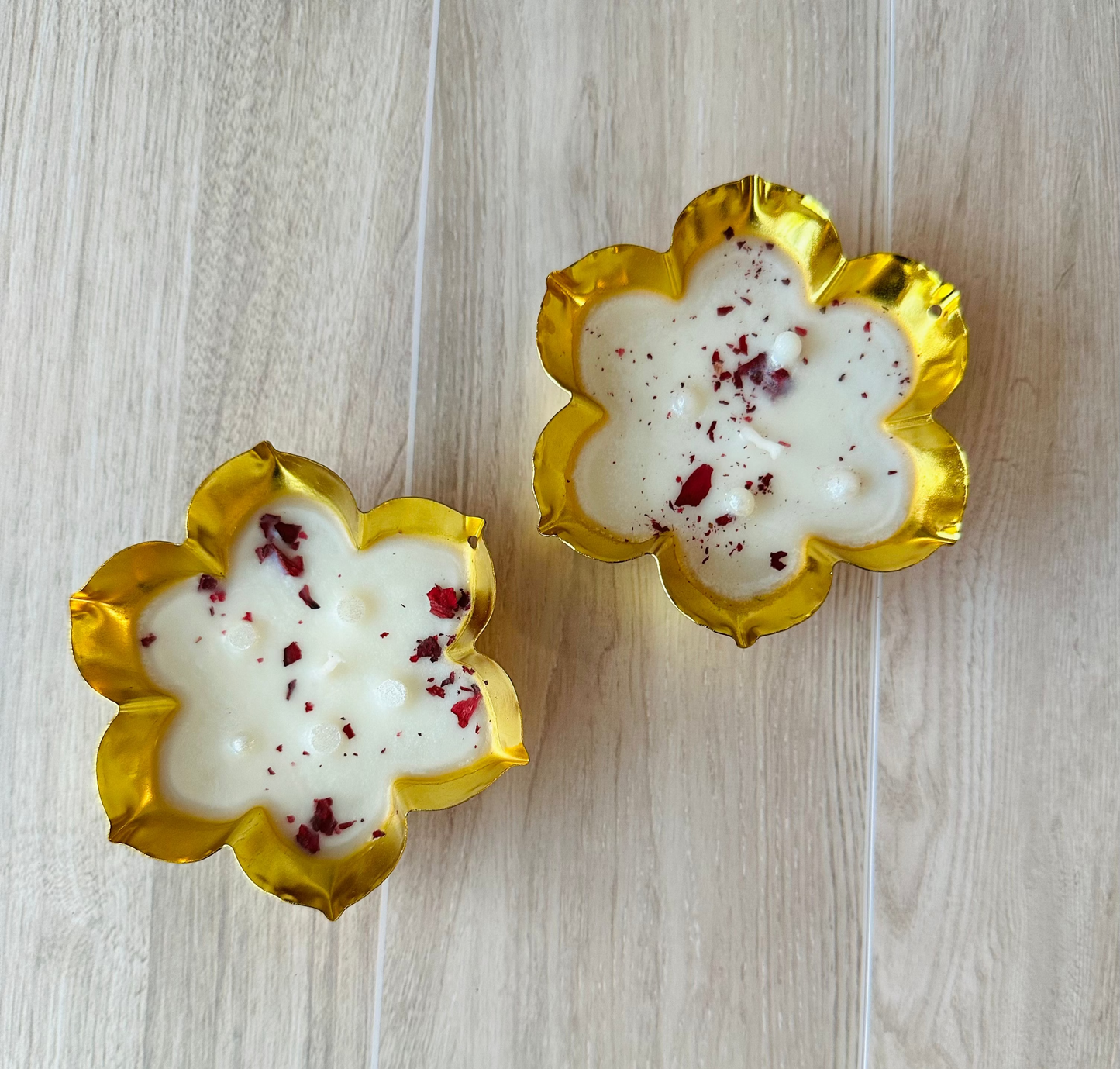 Two flower-shaped candles with gold rims