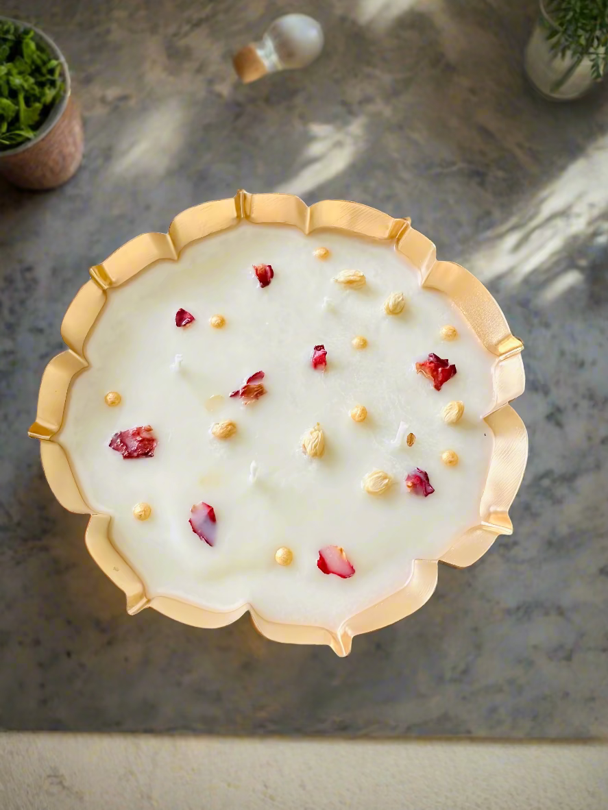 Decorative plate with gold rim and white surface featuring red and gold elements on a wooden surface
