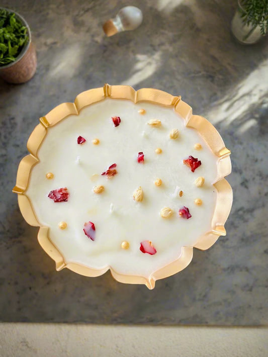 Decorative plate with gold rim and white surface featuring red and gold elements on a wooden surface